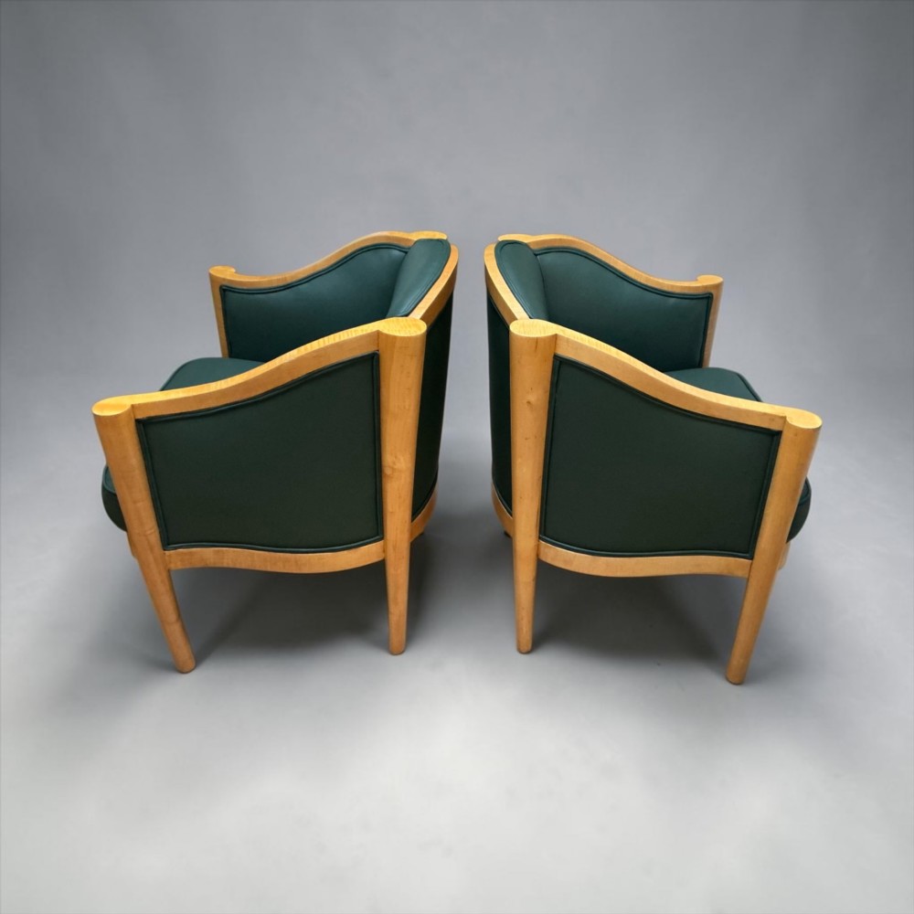 A pair of British Art Deco occasional chairs with curved light honey-toned timber frames and dark green leather upholstered seats and backrests. View VI