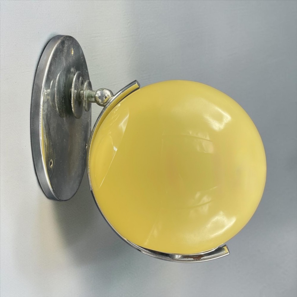 An Art Deco wall light featuring a round stepped chrome wall mount and an adjustable yellow glass shade. View III