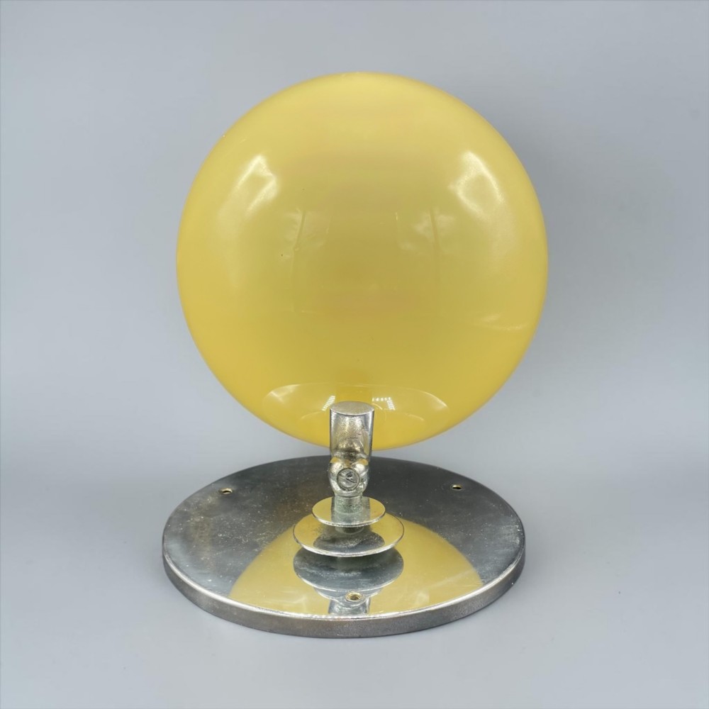 An Art Deco wall light featuring a round stepped chrome wall mount and an adjustable yellow glass shade. View IV