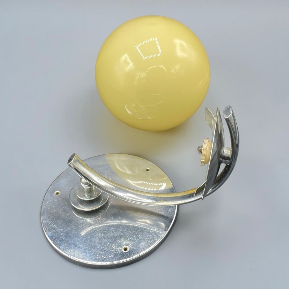 An Art Deco wall light featuring a round stepped chrome wall mount and an adjustable yellow glass shade. View V