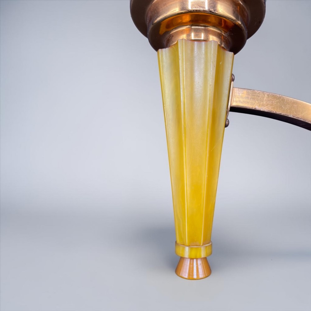 An Art Deco torch wall sconce featuring an amber flame-shaped moulded glass shade set on a yellow stepped stem with a brass mounting arm. View II