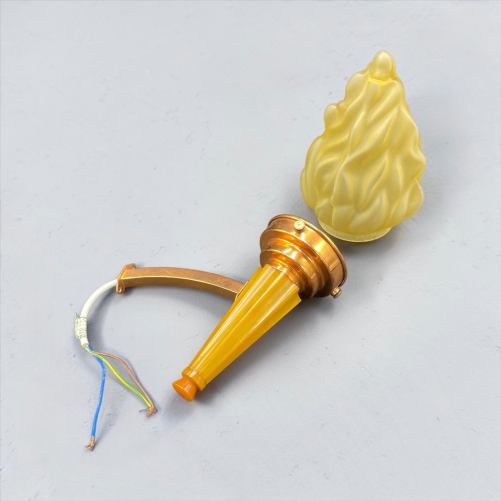 An Art Deco torch wall sconce featuring an amber flame-shaped moulded glass shade set on a yellow stepped stem with a brass mounting arm. View VI