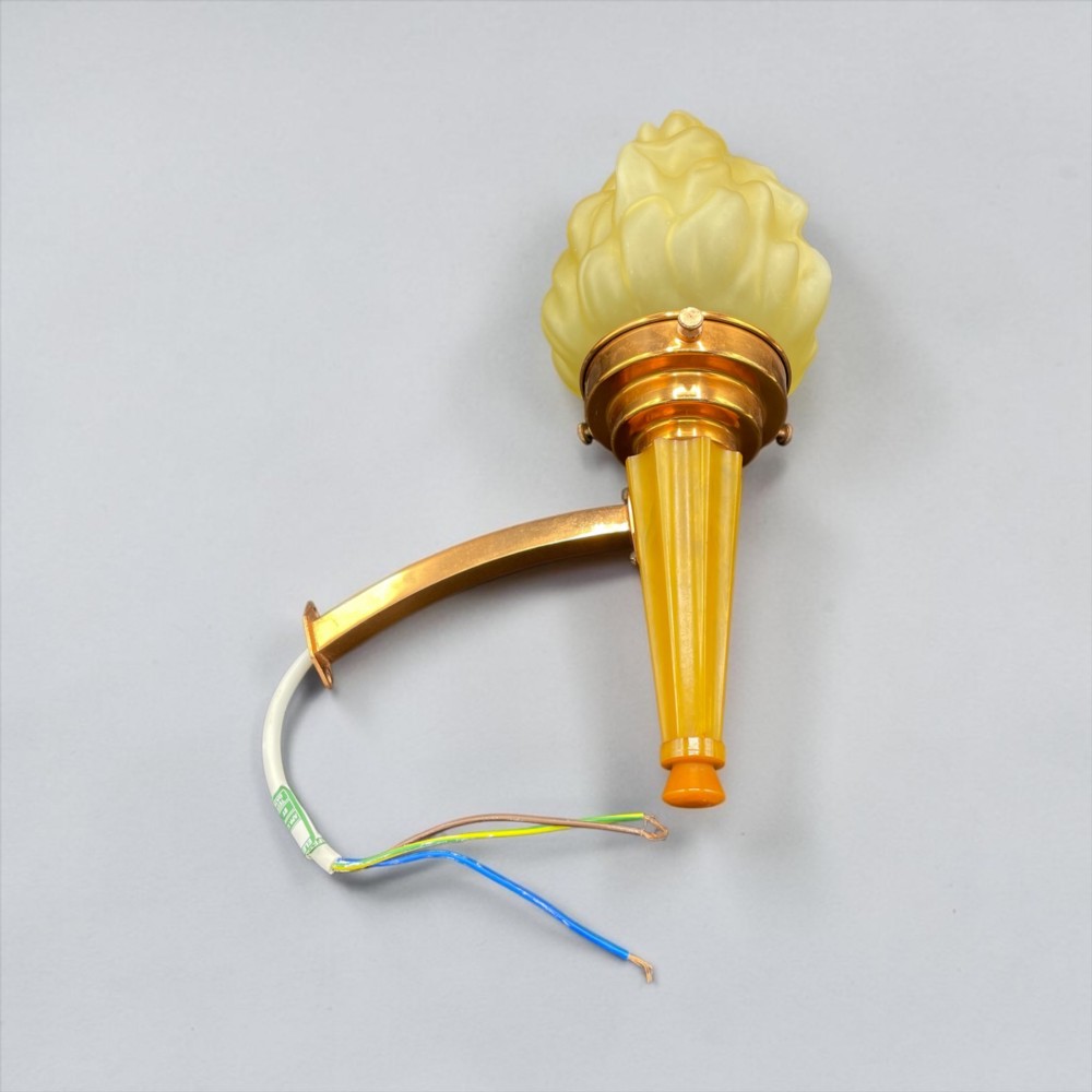 An Art Deco torch wall sconce featuring an amber flame-shaped moulded glass shade set on a yellow stepped stem with a brass mounting arm. View VII