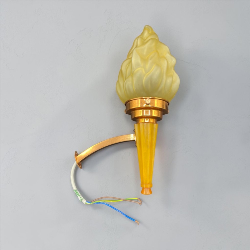 An Art Deco torch wall sconce featuring an amber flame-shaped moulded glass shade set on a yellow stepped stem with a brass mounting arm. View VIII