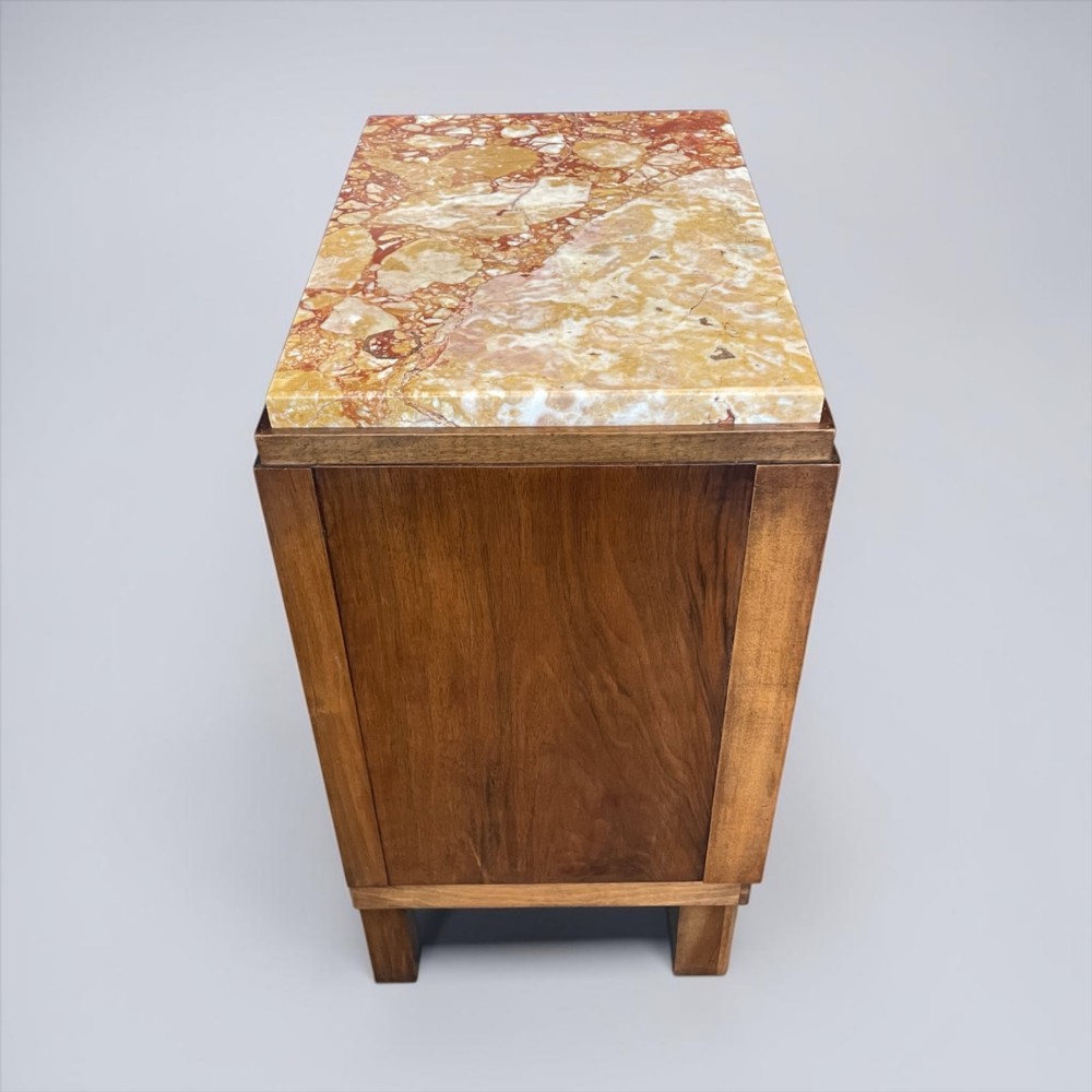 An Art Deco bedside cabinet crafted from polished brown walnut wood featuring a variegated reddish marble top surface and metal handles. View VII