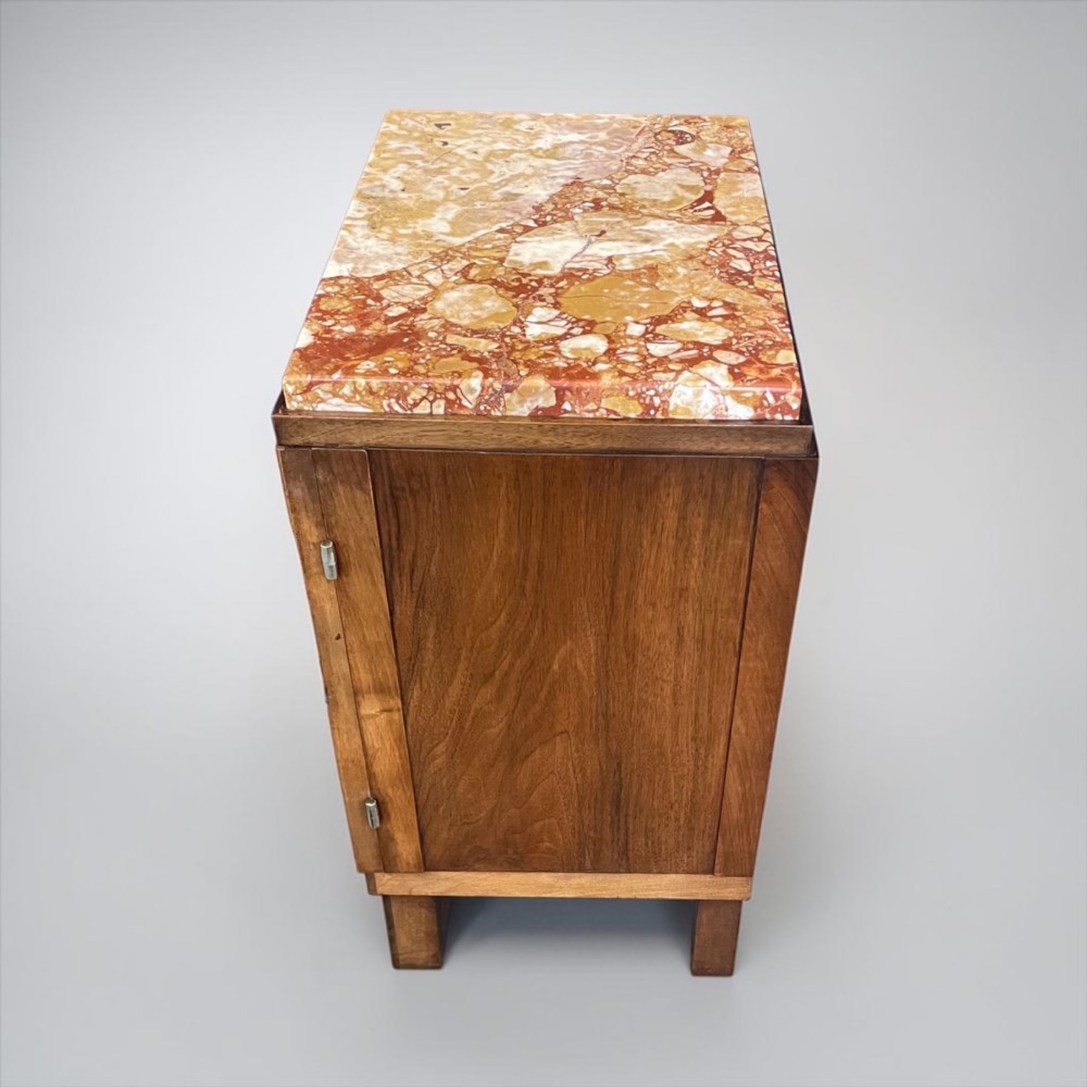 An Art Deco bedside cabinet crafted from polished brown walnut wood featuring a variegated reddish marble top surface and metal handles. View IX