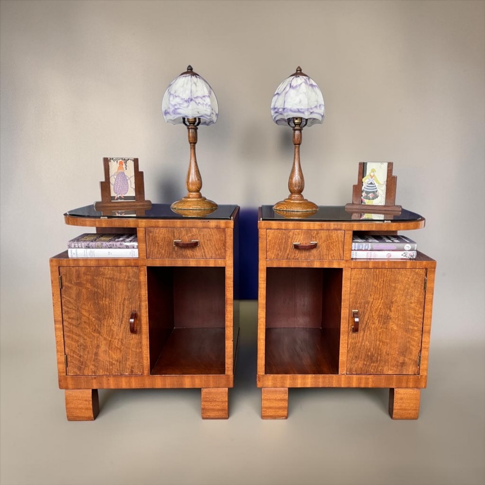 A pair of matching warm brown wooden Art Deco bedside cabinets with asymmetrical drawers, open shelves, lower cupboards, and block feet. View II