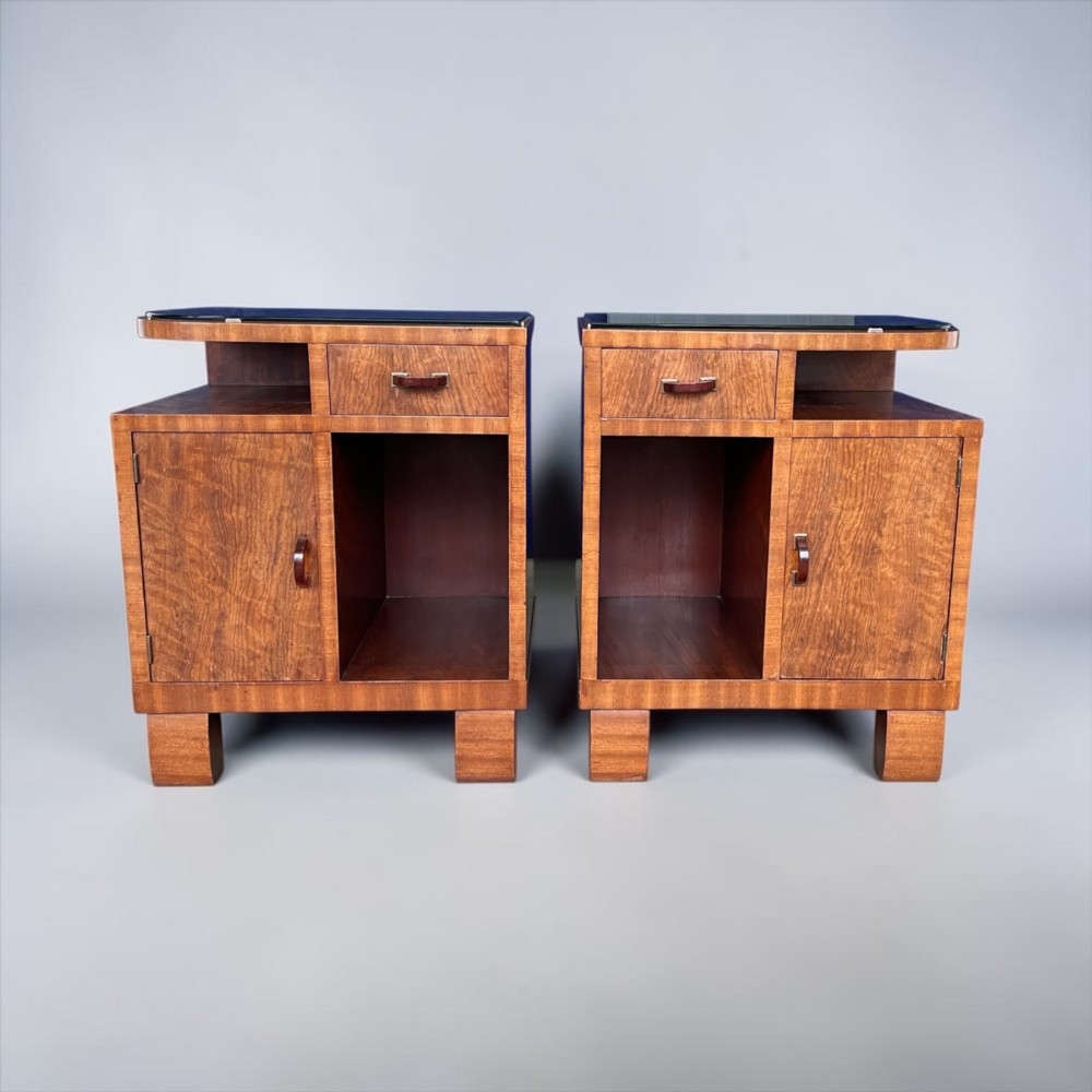 A pair of matching warm brown wooden Art Deco bedside cabinets with asymmetrical drawers, open shelves, lower cupboards, and block feet. View IV
