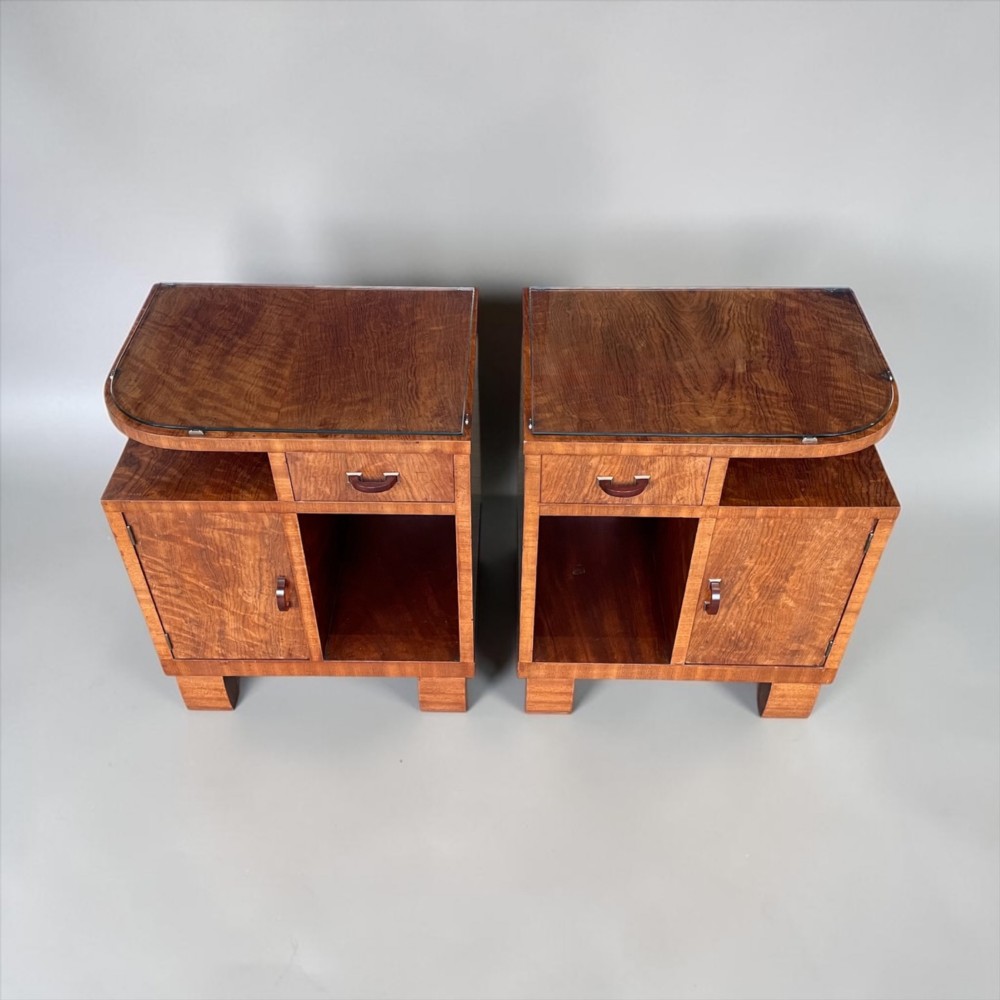 A pair of matching warm brown wooden Art Deco bedside cabinets with asymmetrical drawers, open shelves, lower cupboards, and block feet. View V