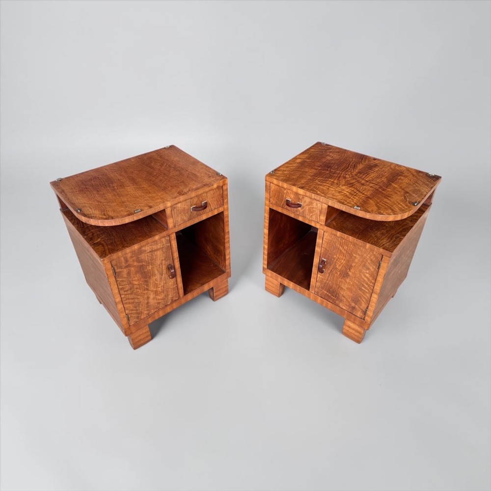 A pair of matching warm brown wooden Art Deco bedside cabinets with asymmetrical drawers, open shelves, lower cupboards, and block feet. View VI