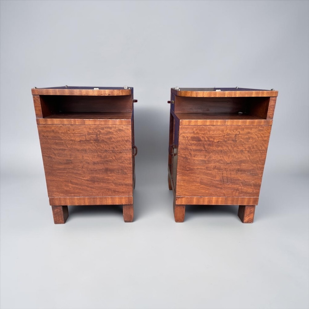 A pair of matching warm brown wooden Art Deco bedside cabinets with asymmetrical drawers, open shelves, lower cupboards, and block feet. View VIII