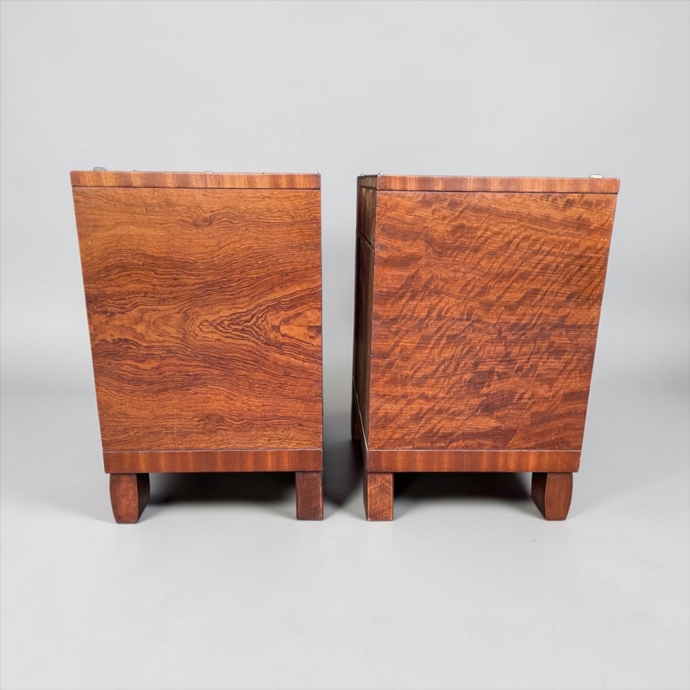 A pair of matching warm brown wooden Art Deco bedside cabinets with asymmetrical drawers, open shelves, lower cupboards, and block feet. View IX