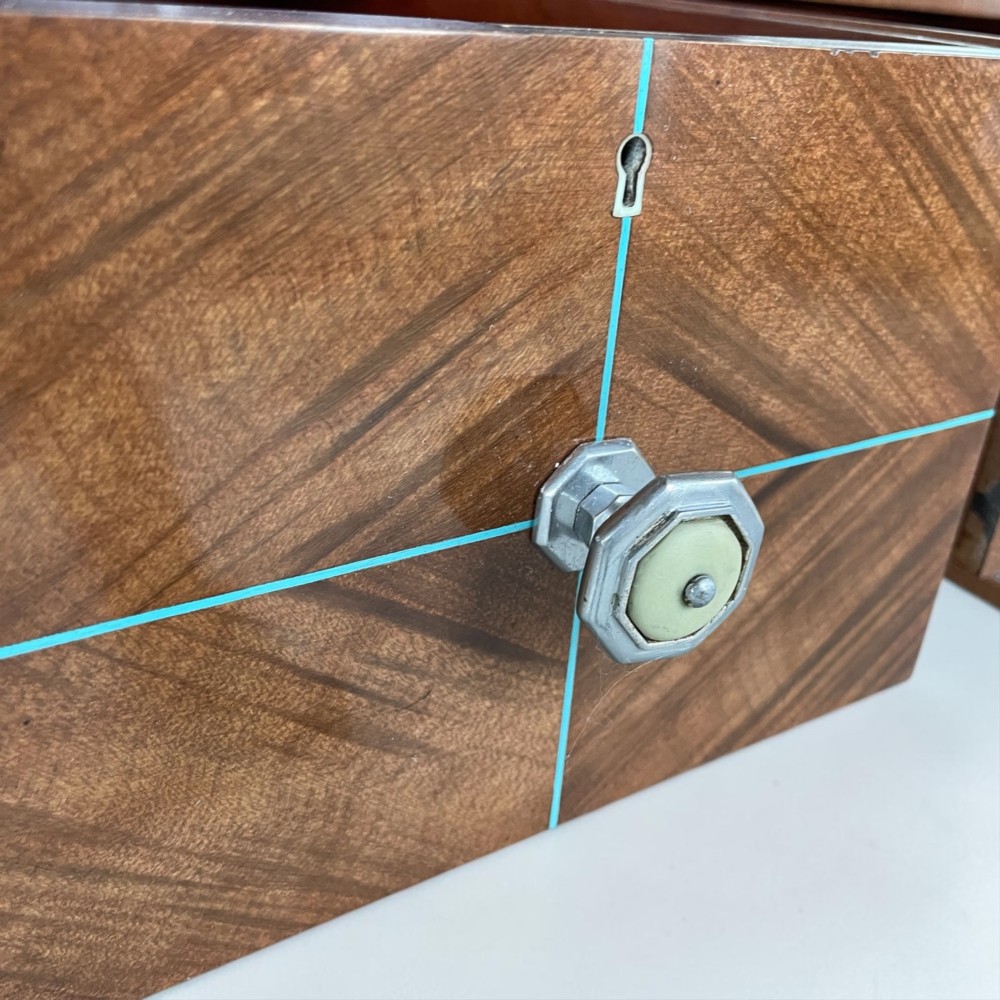 An Art Deco writing desk with geometric chevron parquetry drawer fronts, fine line inlay, and octagonal pulls on slender tapered legs. View V