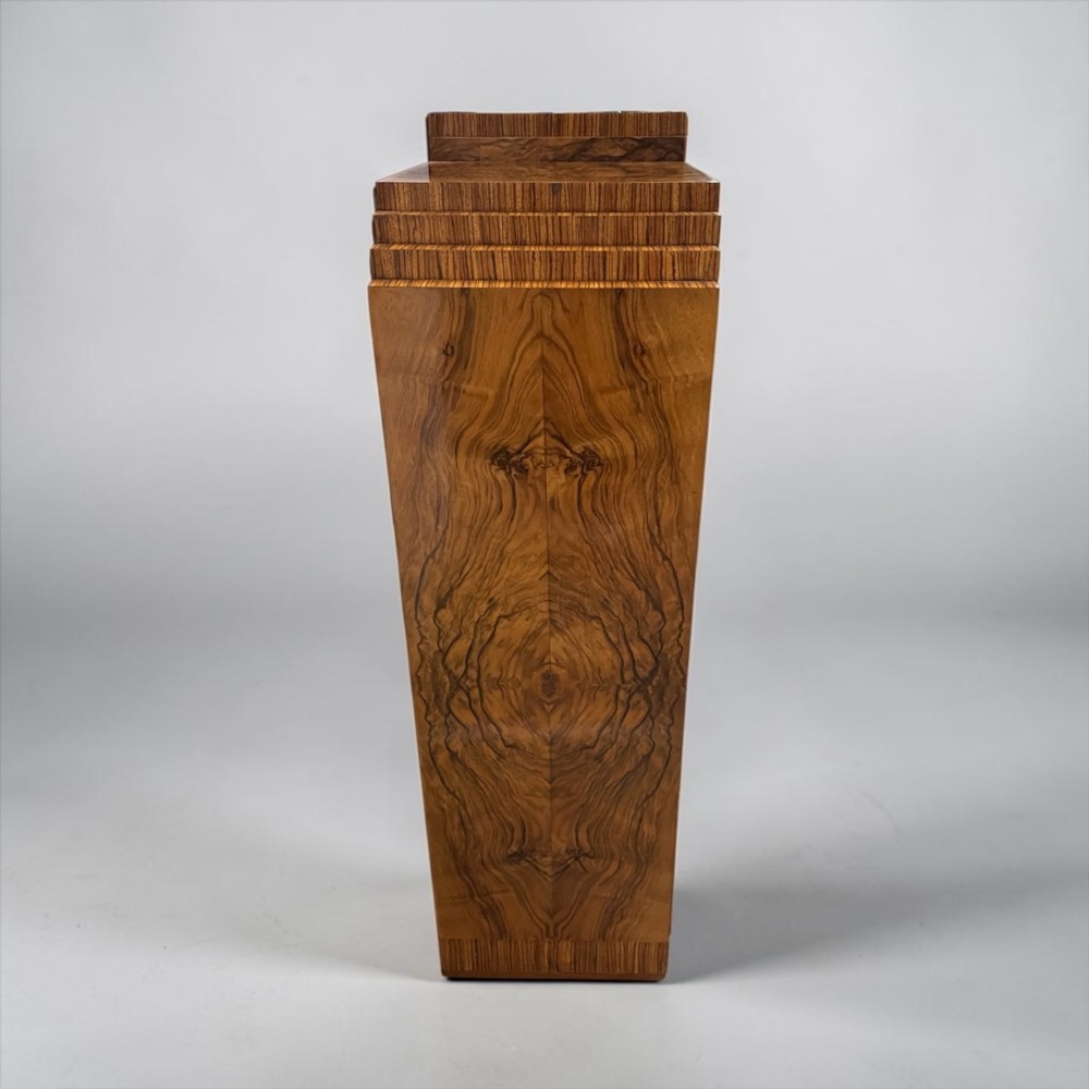 An Art Deco warm brown walnut bookcase featuring a stepped architectural top, three glass doors, and highly figured timber veneer. View IX