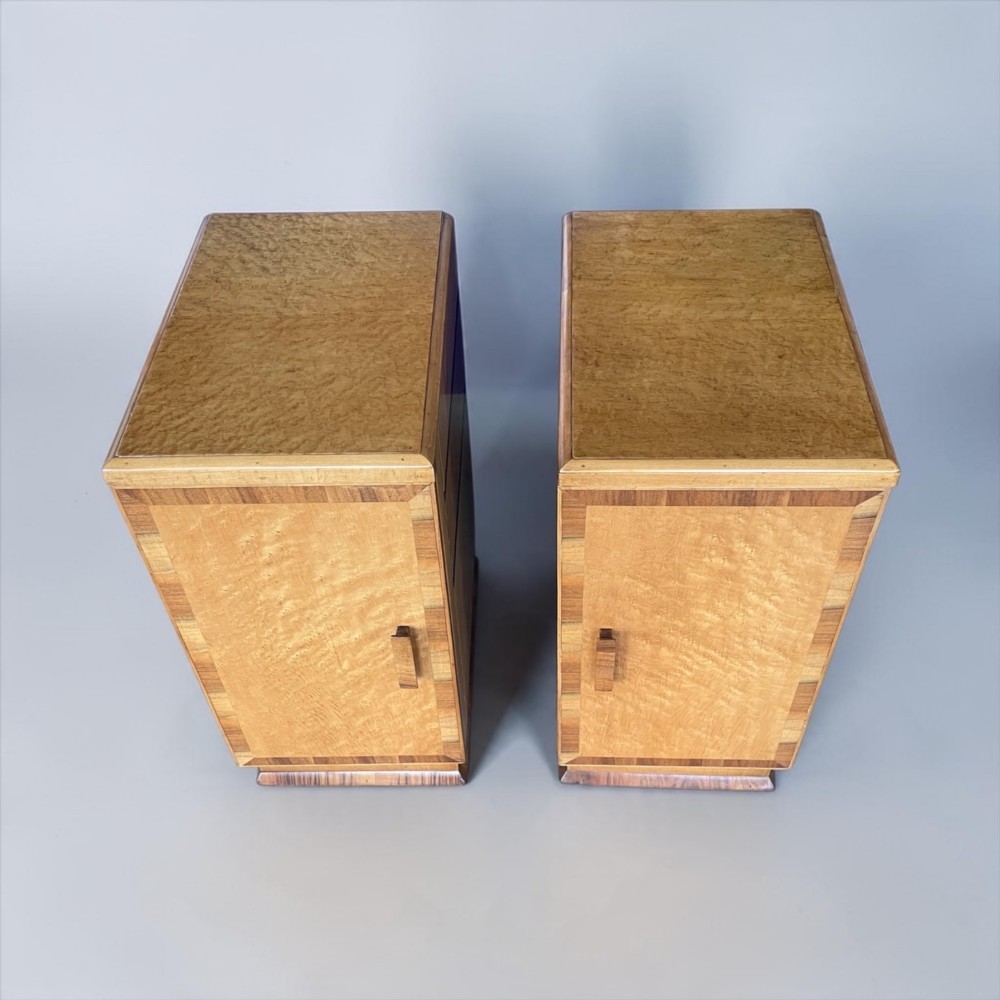 A matching pair of golden burr maple Art Deco bedside tables featuring single door cupboards with wooden block handles and plinth bases. View II