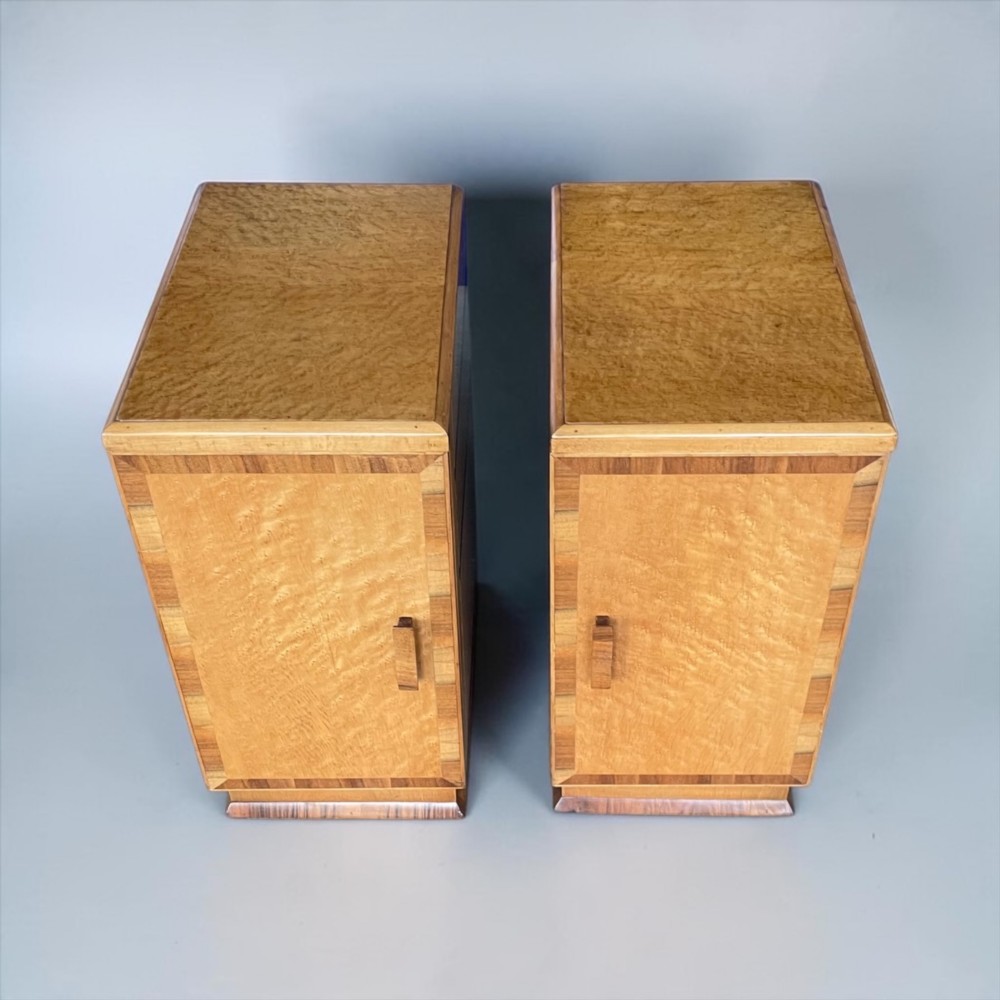 A matching pair of golden burr maple Art Deco bedside tables featuring single door cupboards with wooden block handles and plinth bases. View IV