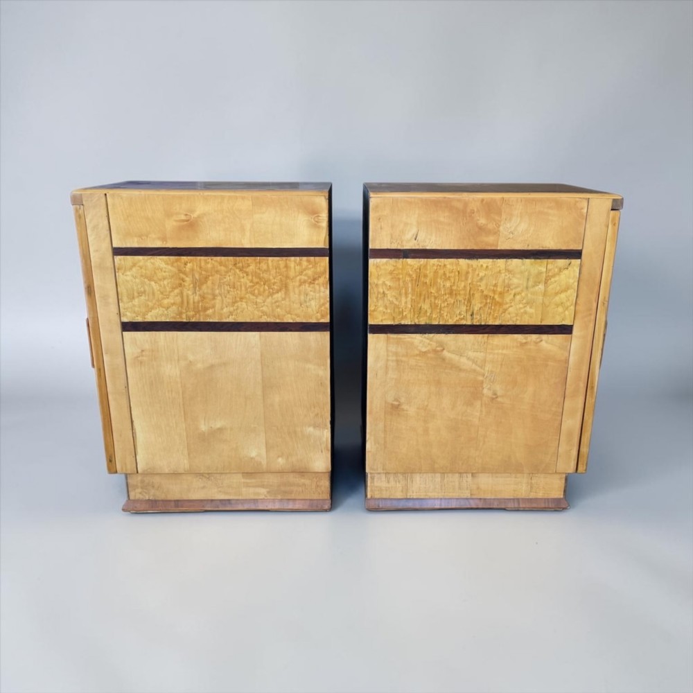 A matching pair of golden burr maple Art Deco bedside tables featuring single door cupboards with wooden block handles and plinth bases. View VII