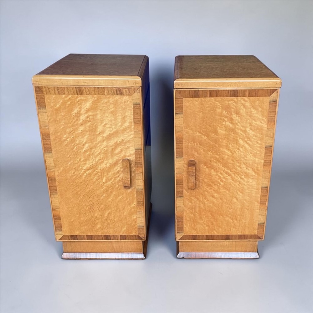A matching pair of golden burr maple Art Deco bedside tables featuring single door cupboards with wooden block handles and plinth bases. View IX