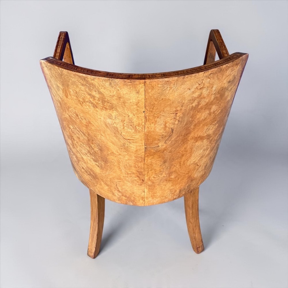 An Art Deco armchair featuring a polished walnut wooden frame, geometric orange patterned upholstery, angular armrests, and tapered legs. View IV