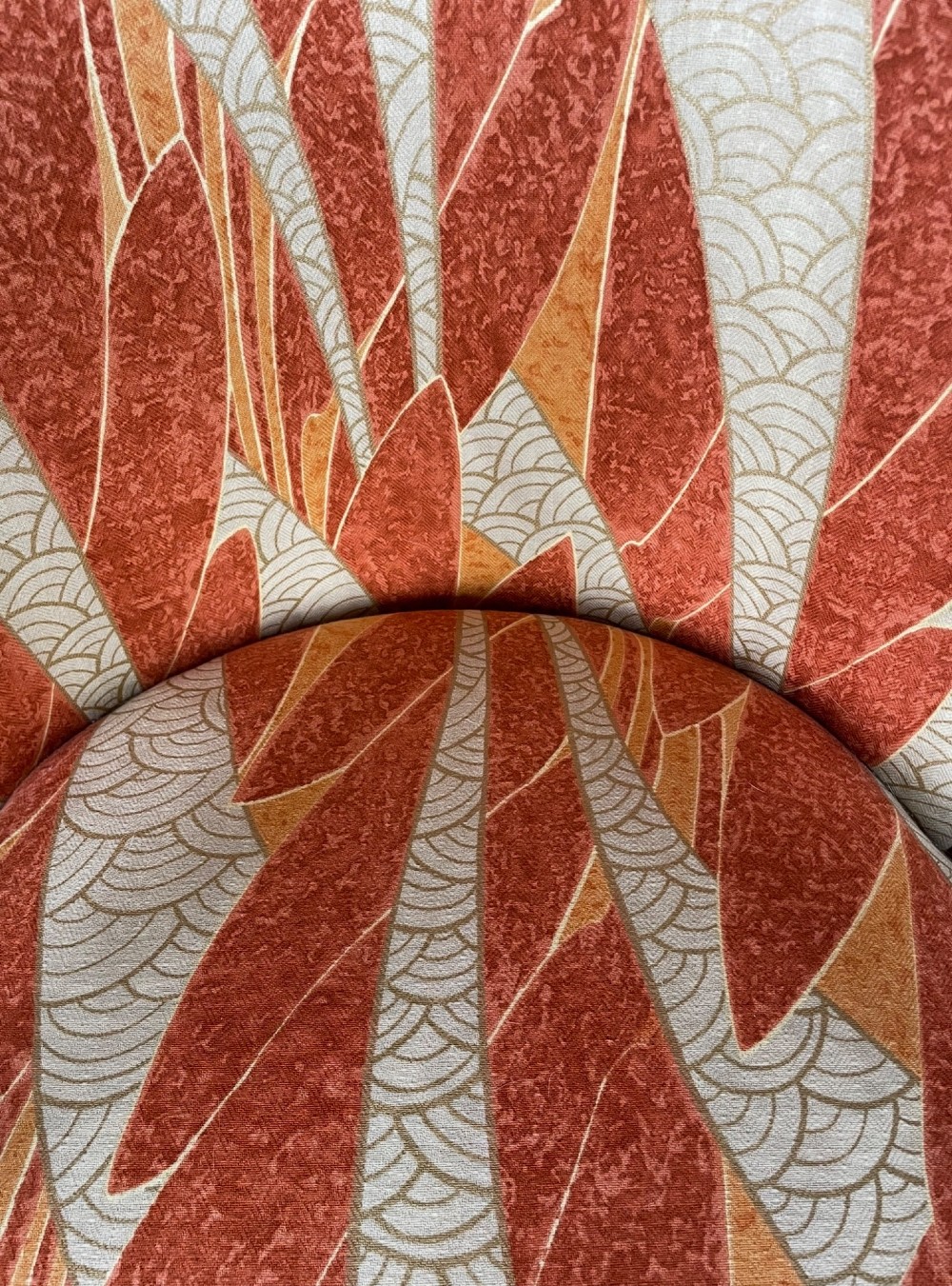 An Art Deco armchair featuring a polished walnut wooden frame, geometric orange patterned upholstery, angular armrests, and tapered legs. View IX