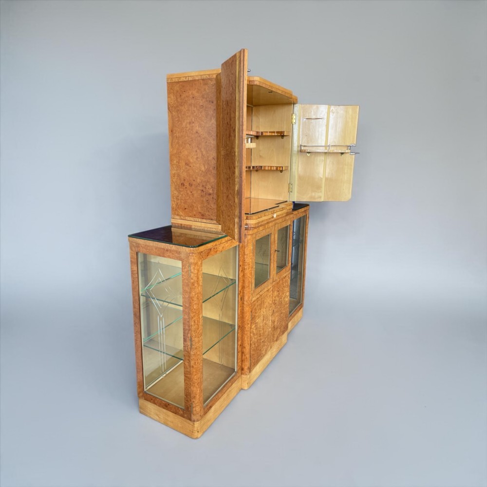 An Art Deco burr walnut cocktail cabinet with open upper doors revealing a mirrored interior, flanked by lower etched glass display sections. View XIV
