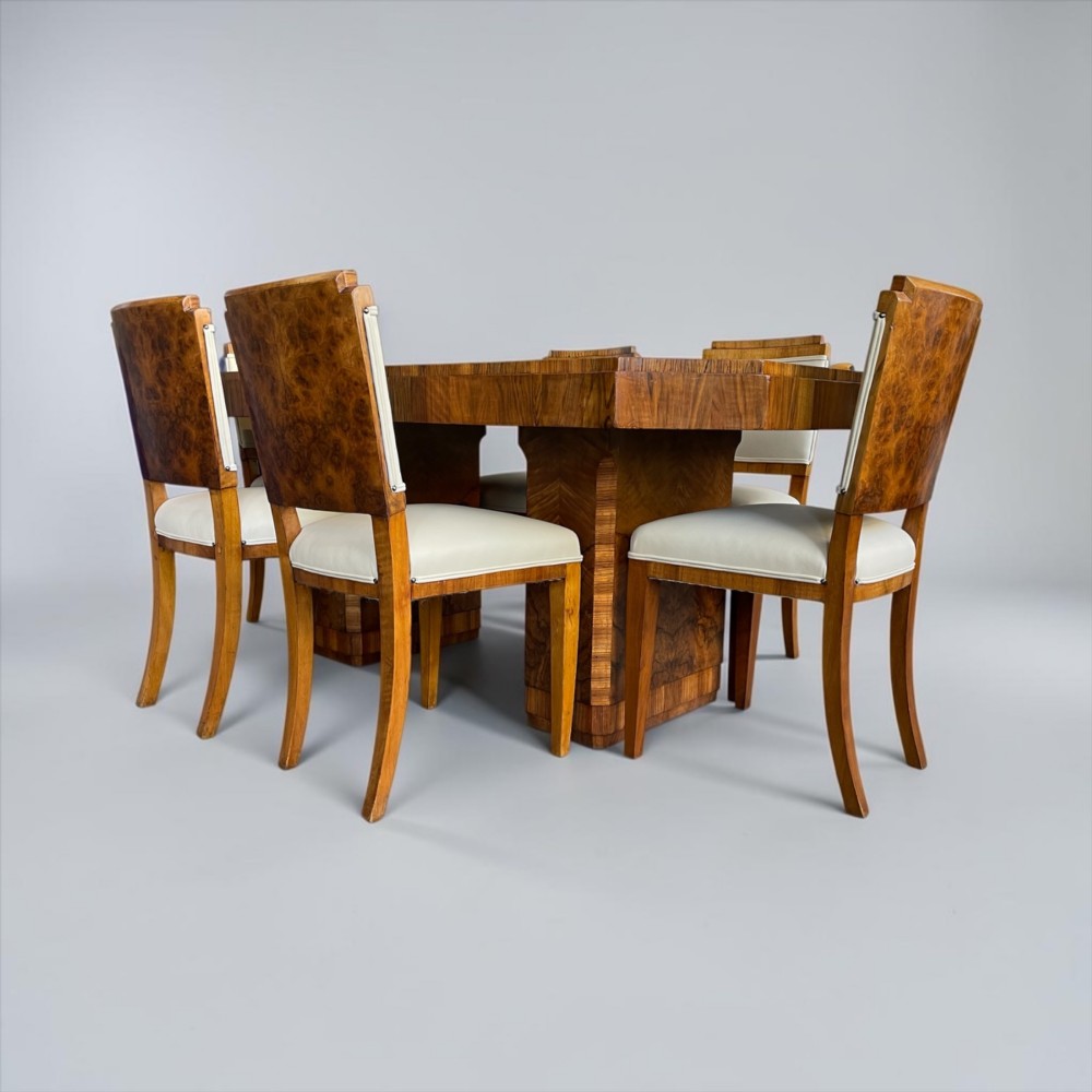 An Art Deco burr walnut dining table featuring a richly figured canted top paired with six matching chairs upholstered in cream leather. View III