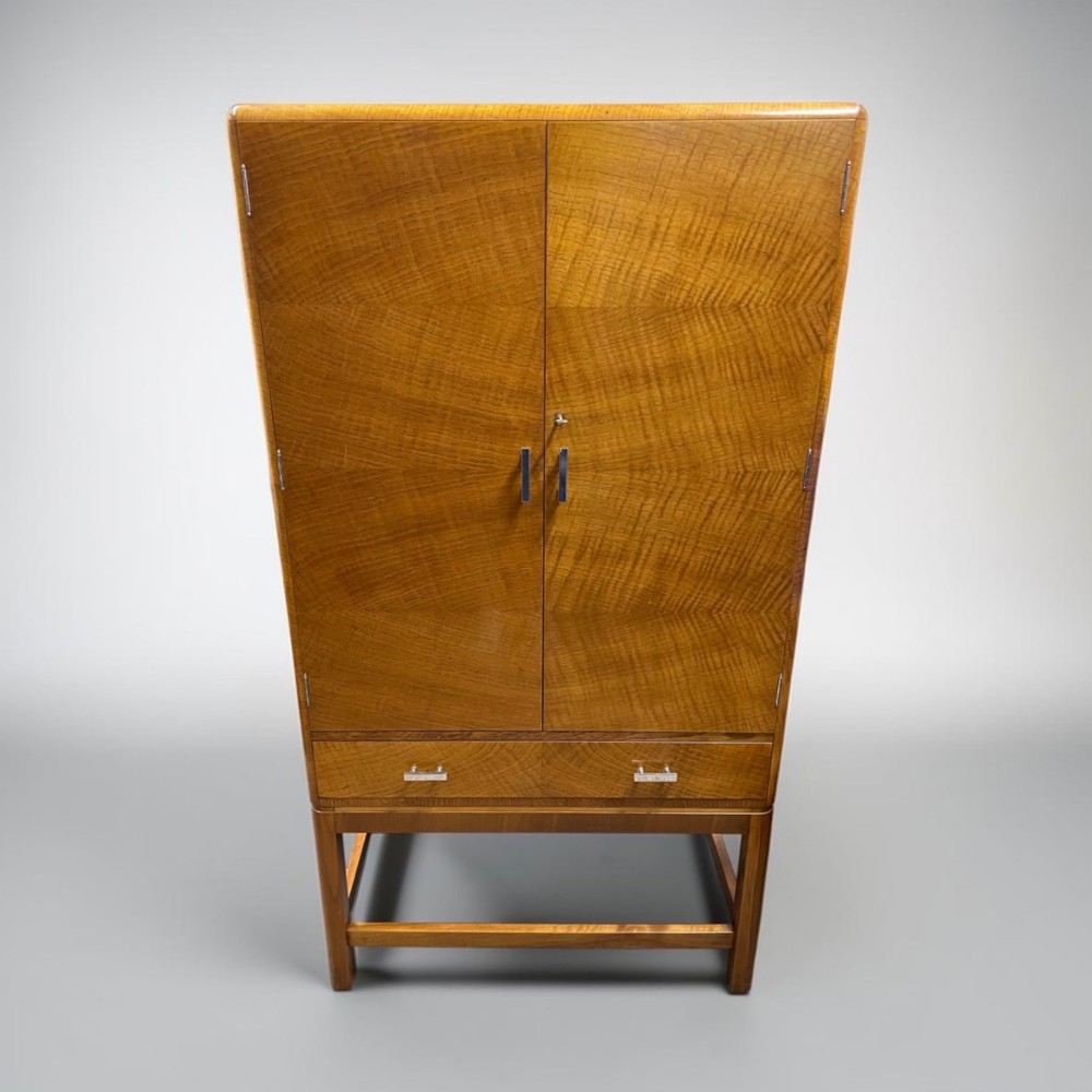An Art Deco golden oak cabinet on stand featuring book-matched chevron wood veneers, two lower drawers, twin cupboard doors, and metal handles. View IV