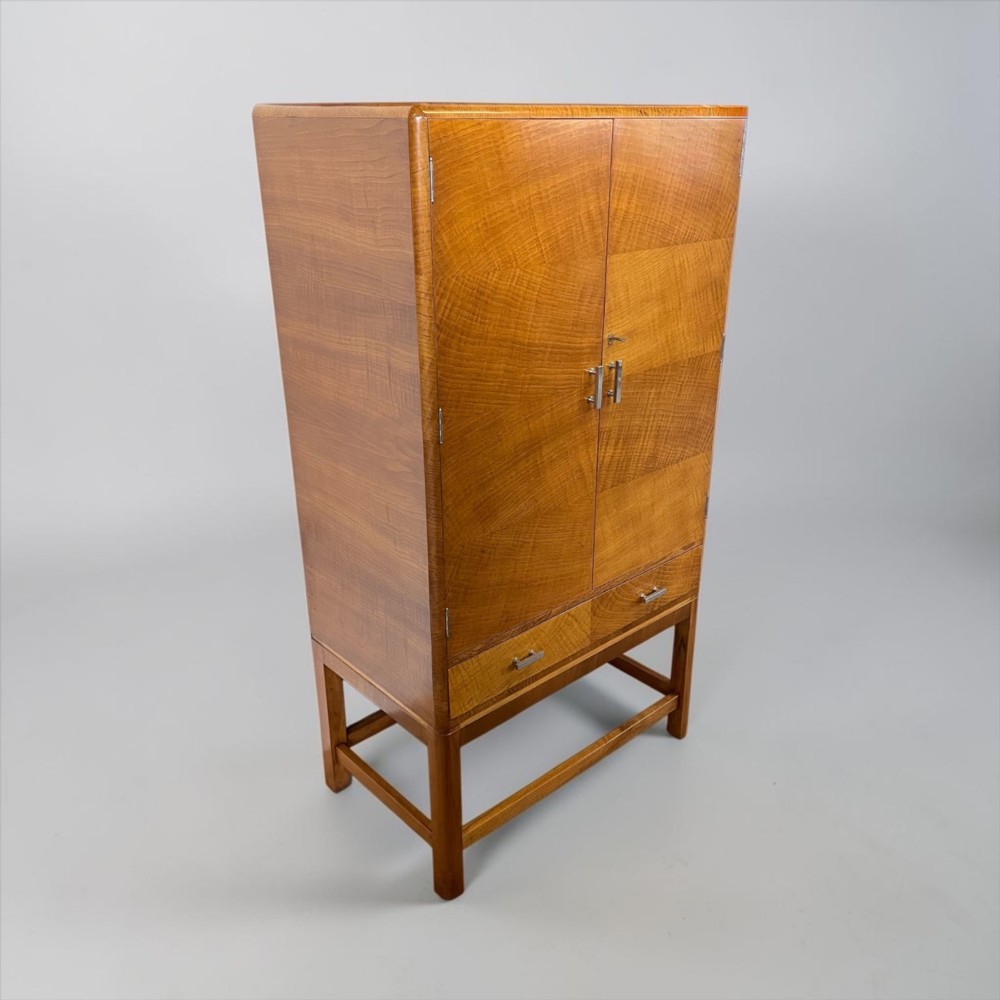 An Art Deco golden oak cabinet on stand featuring book-matched chevron wood veneers, two lower drawers, twin cupboard doors, and metal handles. View IX