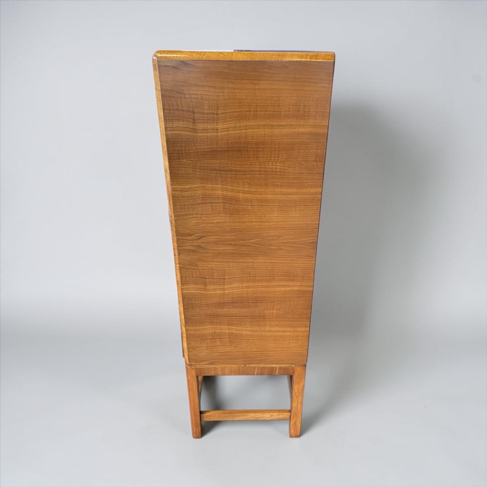 An Art Deco golden oak cabinet on stand featuring book-matched chevron wood veneers, two lower drawers, twin cupboard doors, and metal handles. View XII