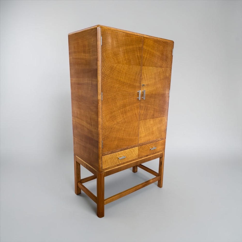 An Art Deco golden oak cabinet on stand featuring book-matched chevron wood veneers, two lower drawers, twin cupboard doors, and metal handles. View XIV