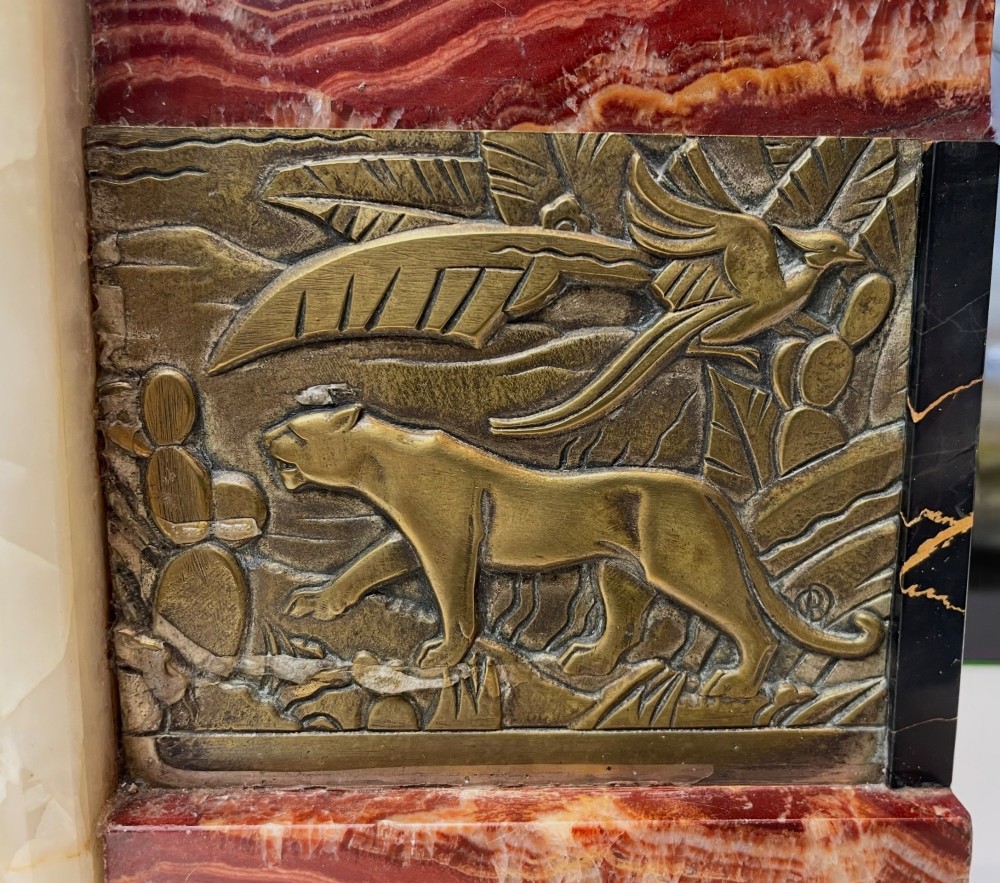 An Art Deco stepped mantel clock crafted from cream onyx and red marble with relief bronze panels depicting gazelles and a panther. View III