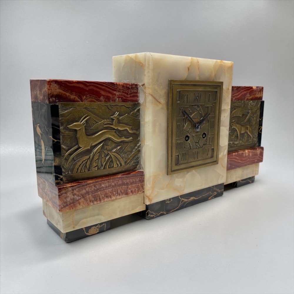 An Art Deco stepped mantel clock crafted from cream onyx and red marble with relief bronze panels depicting gazelles and a panther. View V