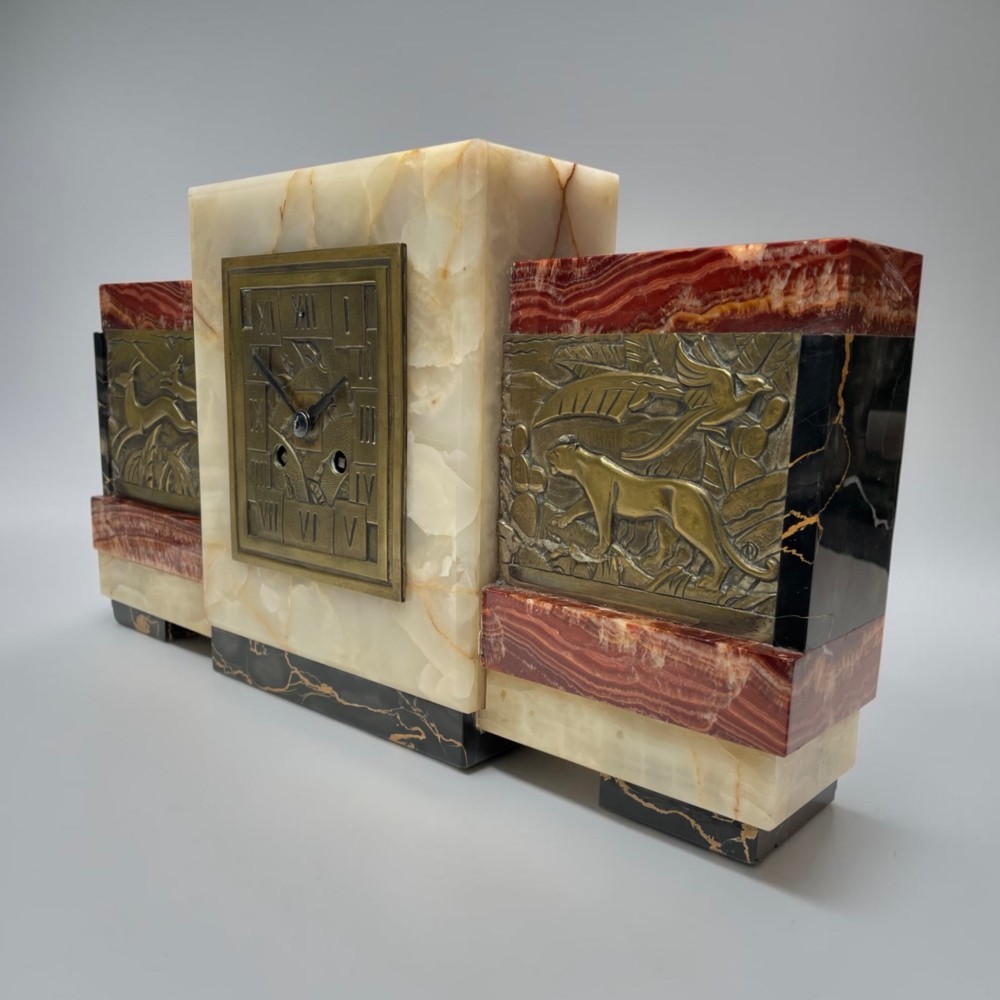 An Art Deco stepped mantel clock crafted from cream onyx and red marble with relief bronze panels depicting gazelles and a panther. View VI
