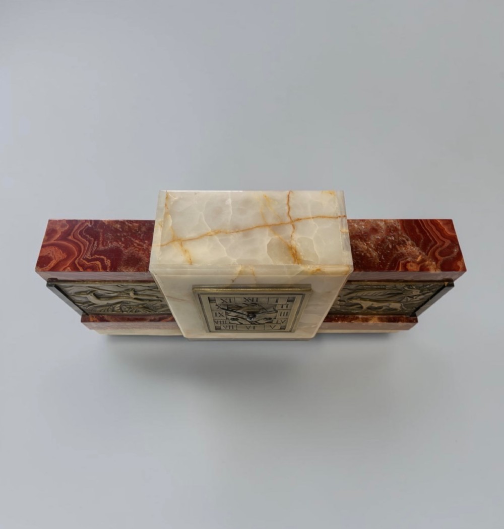 An Art Deco stepped mantel clock crafted from cream onyx and red marble with relief bronze panels depicting gazelles and a panther. View VII