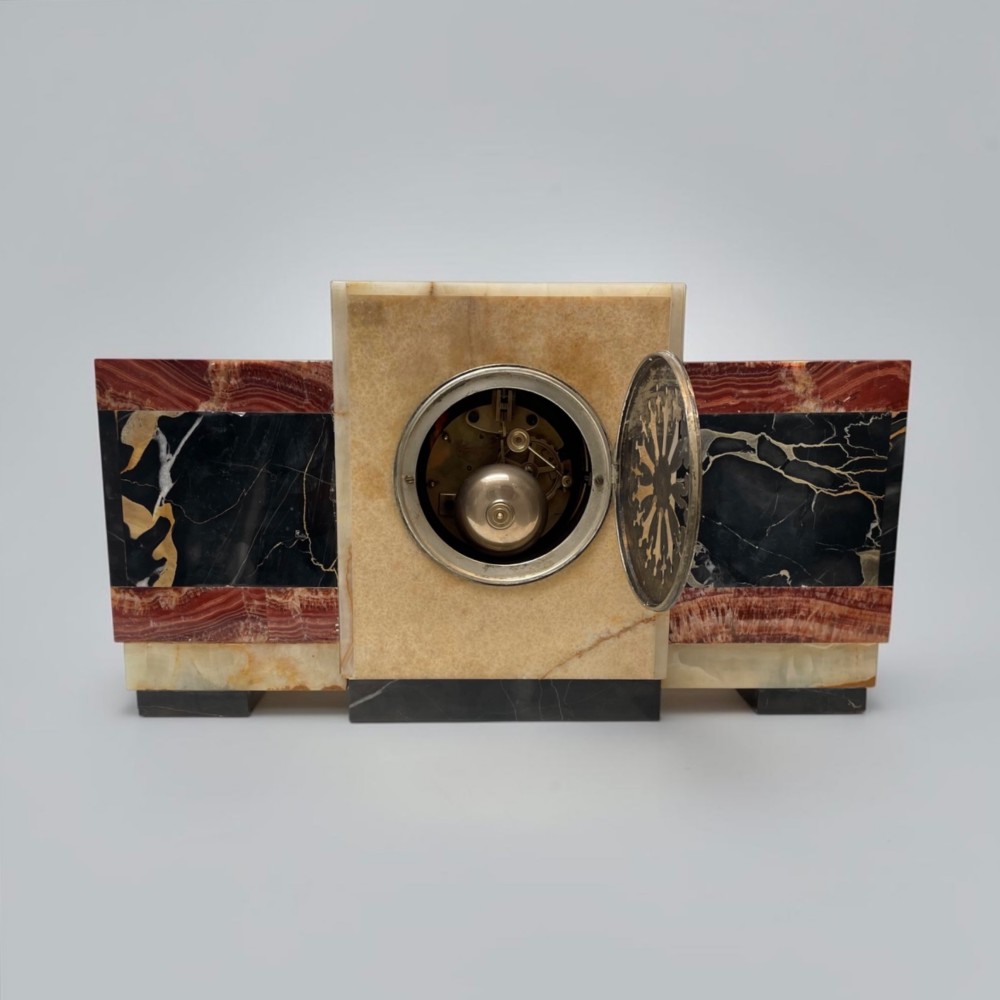 An Art Deco stepped mantel clock crafted from cream onyx and red marble with relief bronze panels depicting gazelles and a panther. View IX