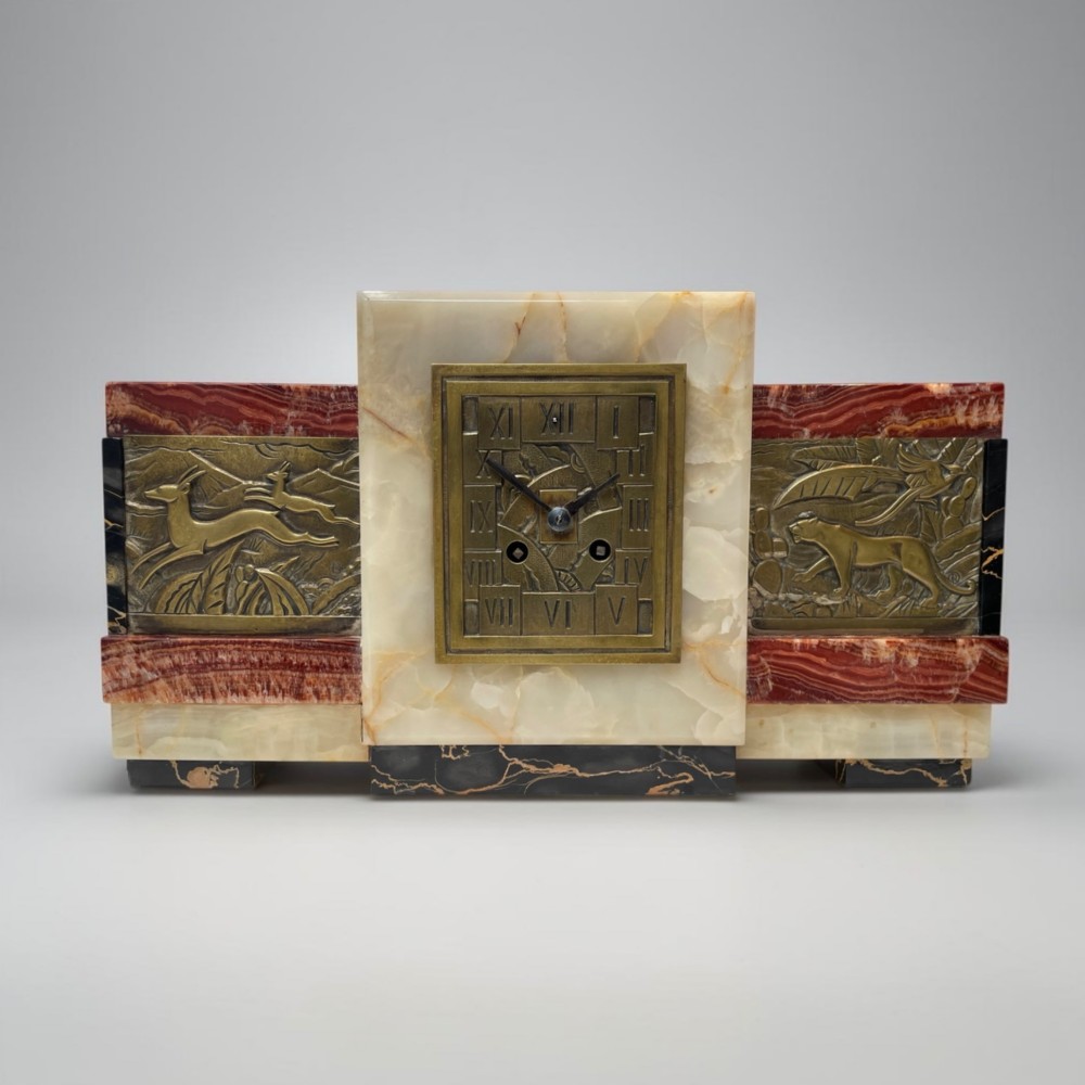 An Art Deco stepped mantel clock crafted from cream onyx and red marble with relief bronze panels depicting gazelles and a panther. View X