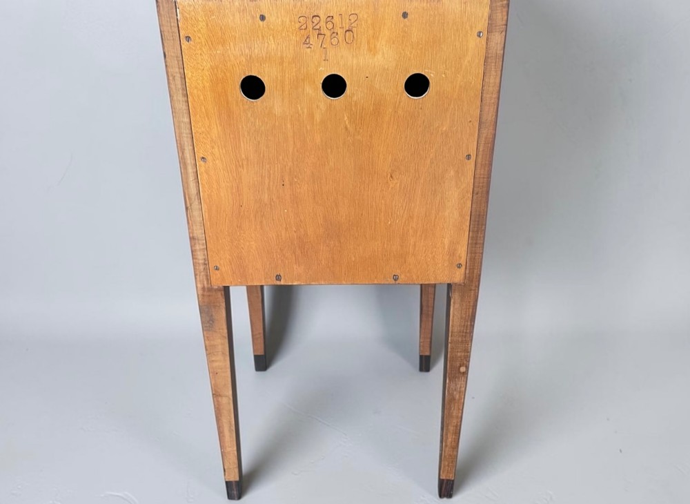 An Art Deco figured walnut bedside table featuring a raised gallery back, geometric parquetry double doors, and slender tapered legs. View VII