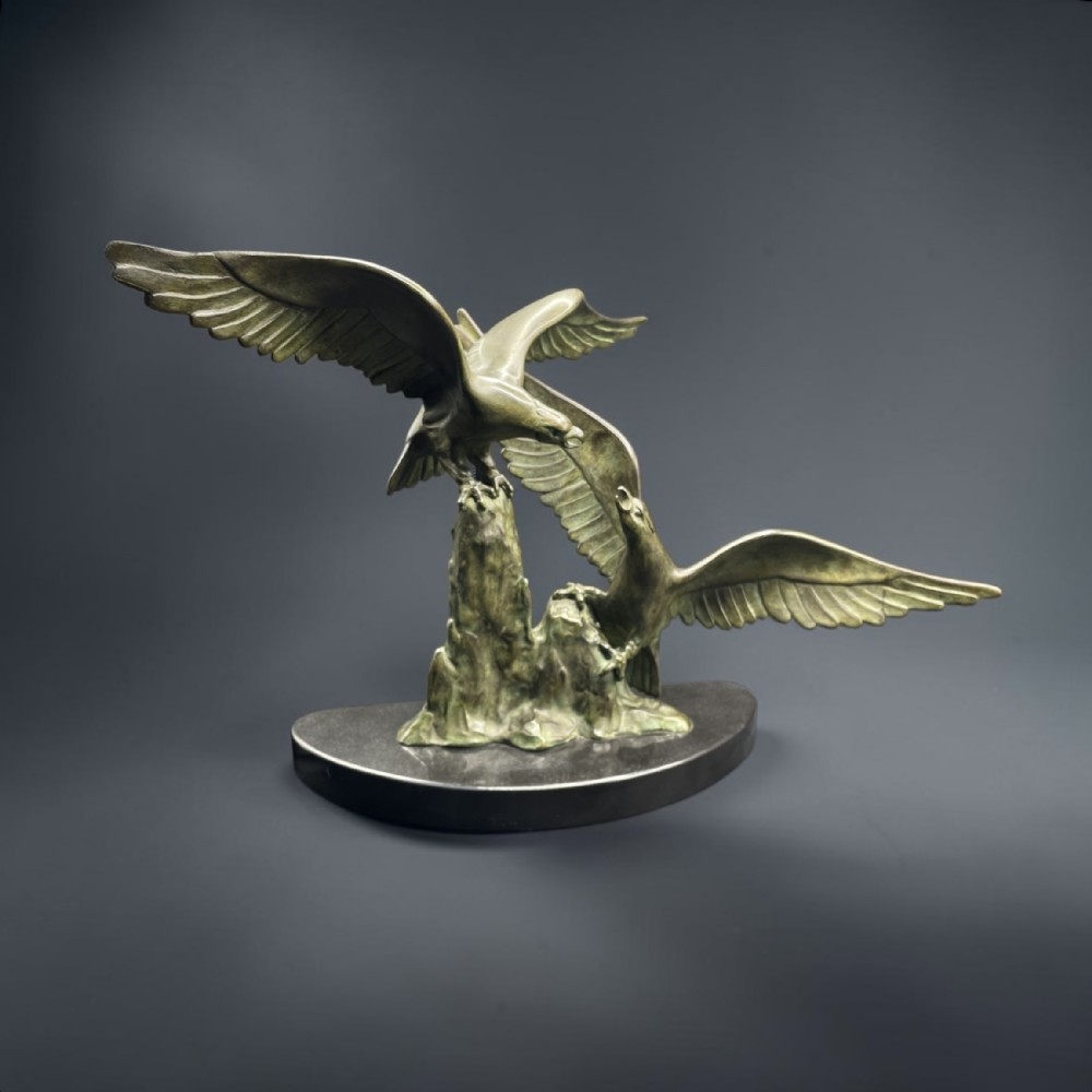 An Art Deco patinated bronze sculpture depicting two eagles with outstretched wings mounted on a rocky outcrop and dark marble plinth.