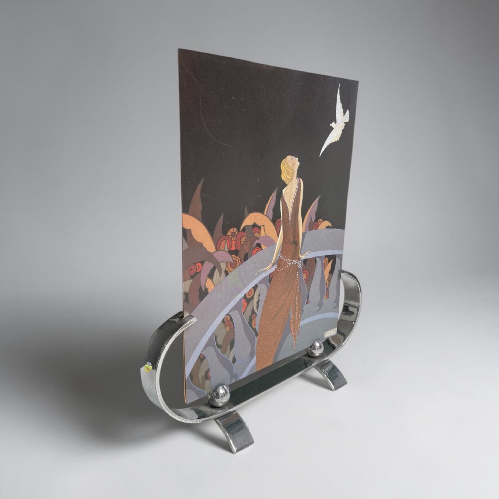 An Art Deco polished chrome picture frame featuring a curved base with spherical accents, holding a paper illustration print.