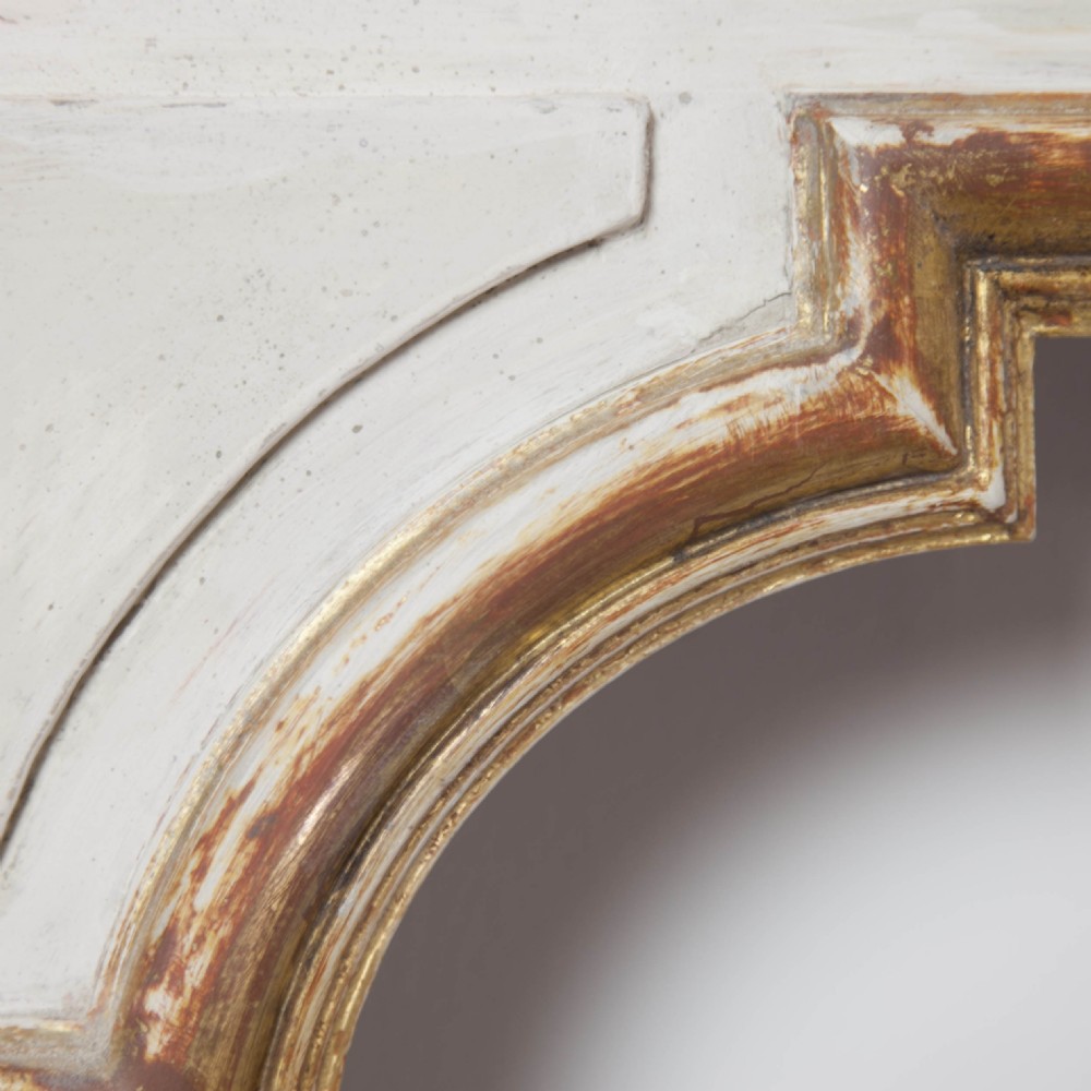 A matching pair of Neoclassical wall mirrors featuring cream painted frames with gilded pediments, scroll cresting, and rectangular mirror glass. View II