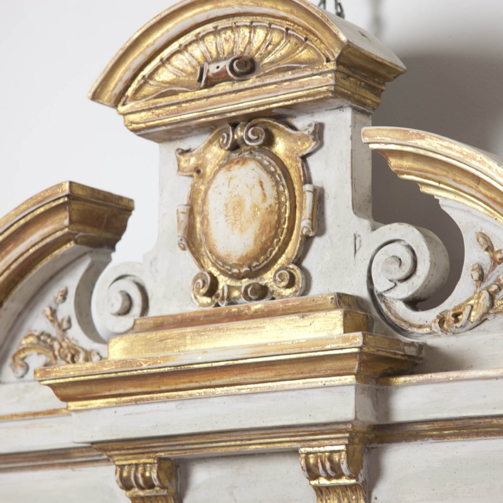 A matching pair of Neoclassical wall mirrors featuring cream painted frames with gilded pediments, scroll cresting, and rectangular mirror glass. View VI