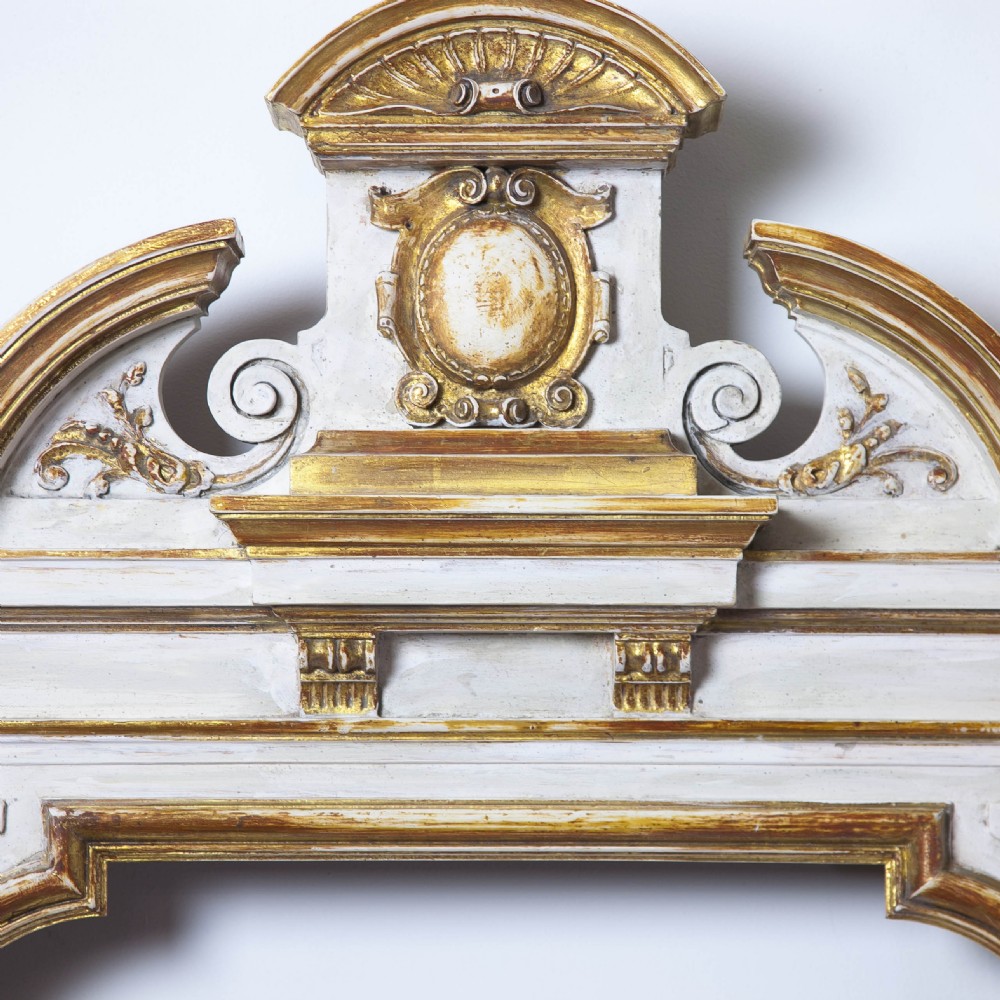 A matching pair of Neoclassical wall mirrors featuring cream painted frames with gilded pediments, scroll cresting, and rectangular mirror glass. View VII