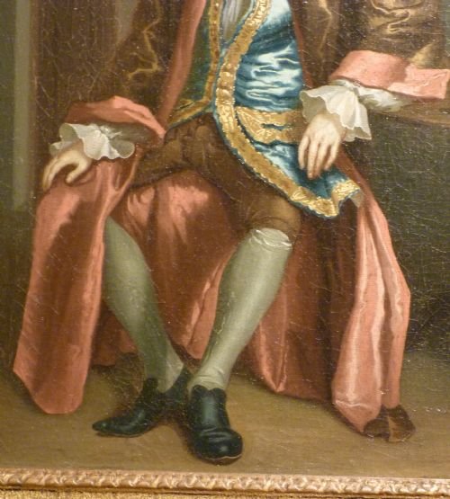 fig 2. An 18th-century oil painting depicting a seated gentleman in a blue embroidered waistcoat alongside a lady in a silver satin dress, set within an ornate carved giltwood frame.