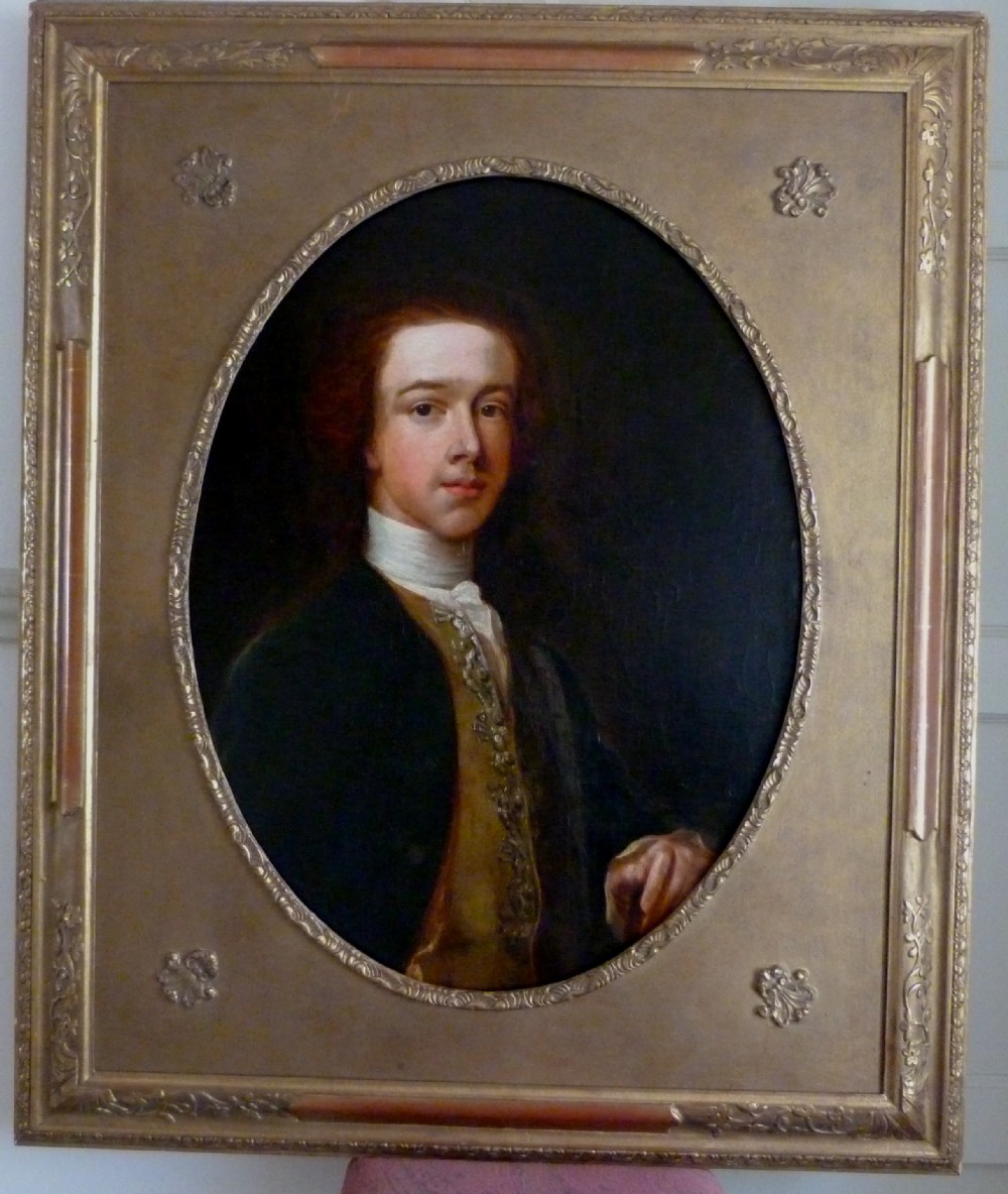 An 18th-century oil painting depicting a young man in Georgian attire set within an oval aperture inside a gilded rectangular frame.