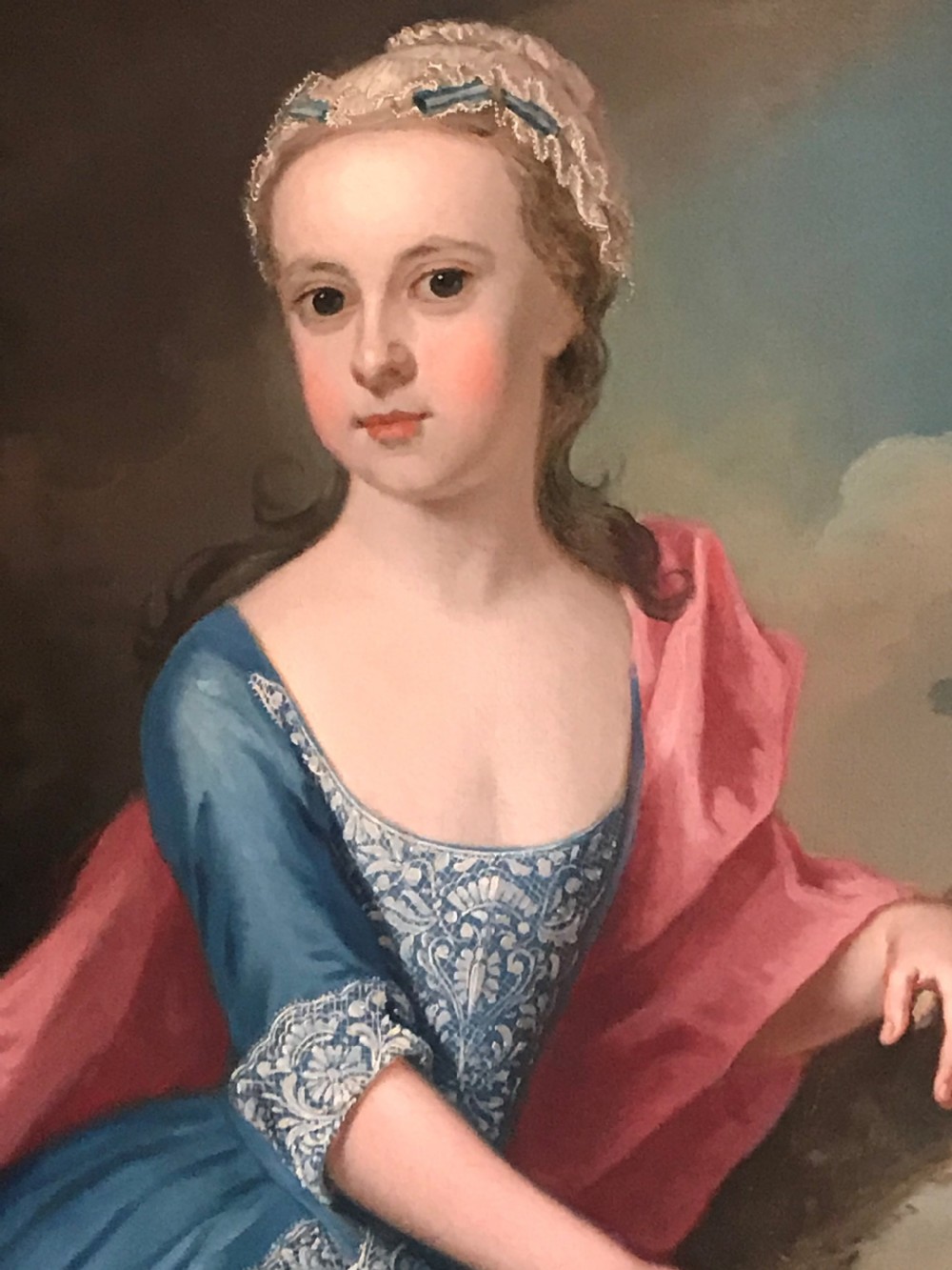 An 18th-century oil painting on canvas depicting a young girl in a blue dress and pink mantle feeding leaves to a deer, set within a carved giltwood frame. View III