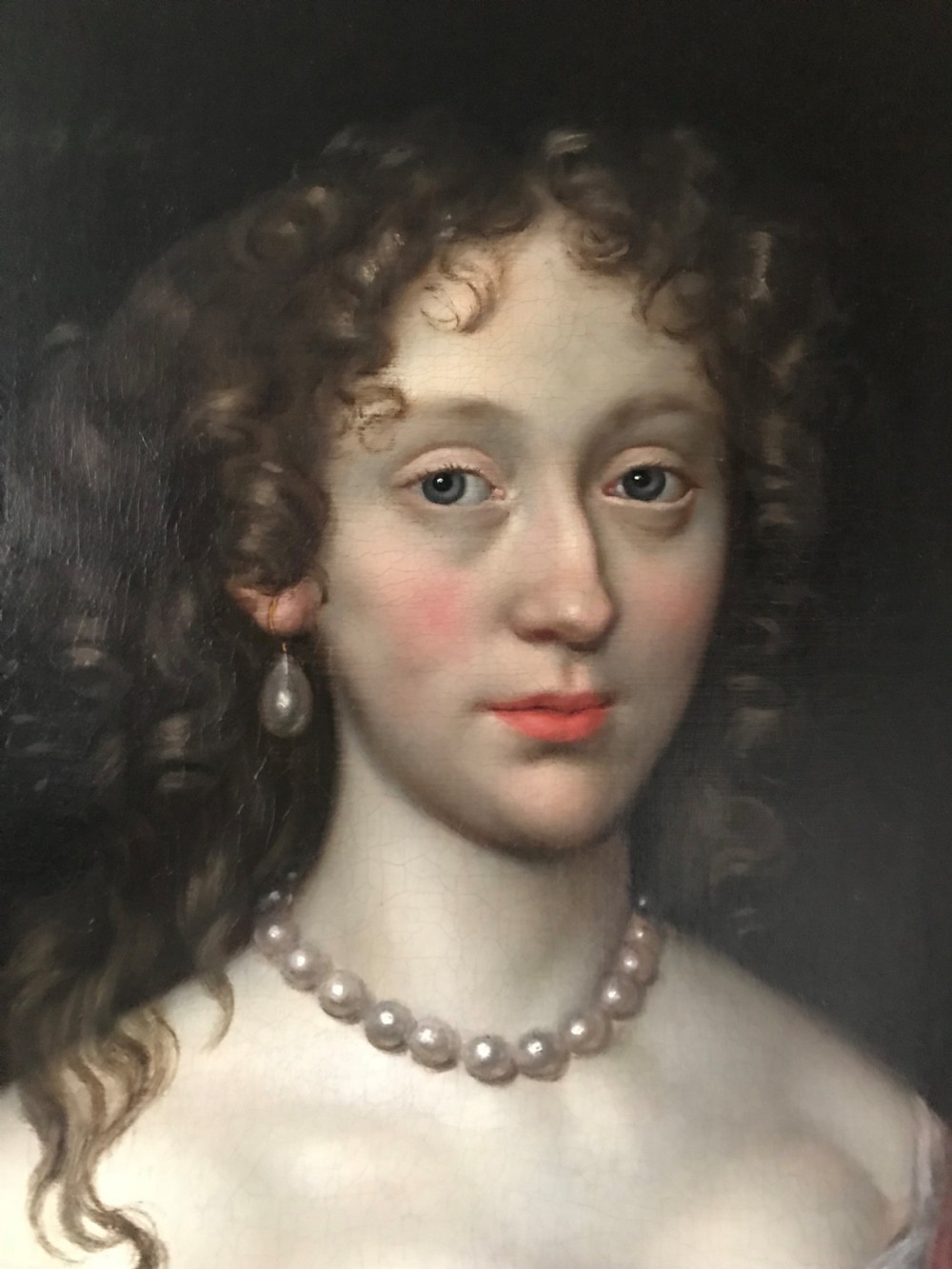 An antique seventeenth-century oil portrait of a noblewoman in a blue dress and pearl jewellery set within an ornate carved giltwood frame. View III