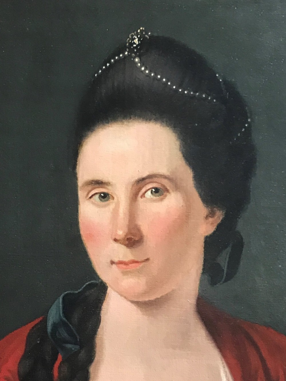 An 18th-century oil portrait painting of a lady wearing a red dress with a pink floral corsage, displayed within a moulded giltwood frame. View II