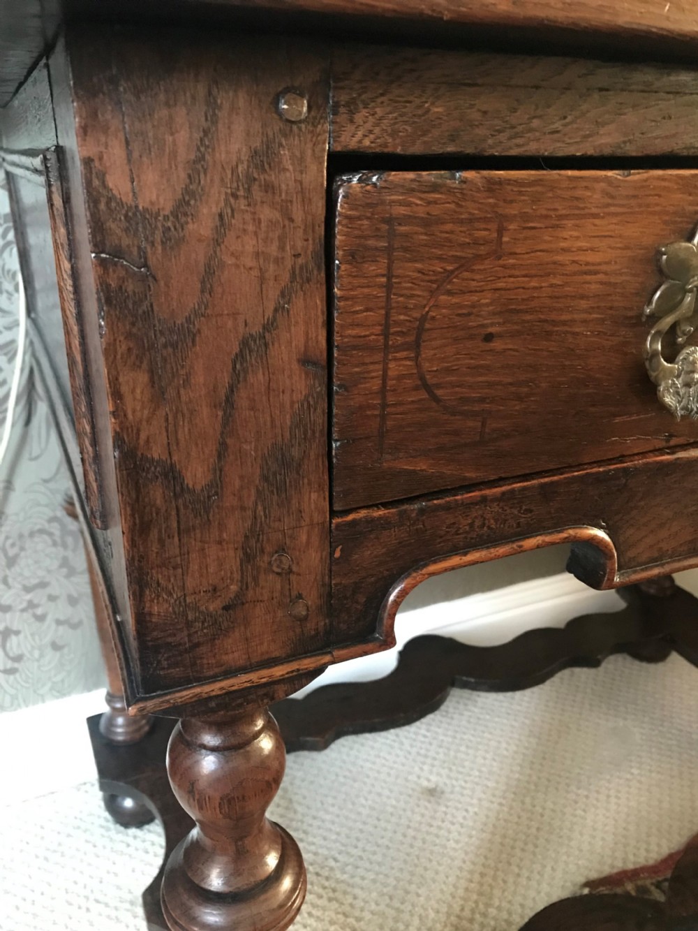 A dark oak side table with a single drawer featuring brass drop handles, a shaped apron, turned baluster legs, and a wavy stretcher base. View III