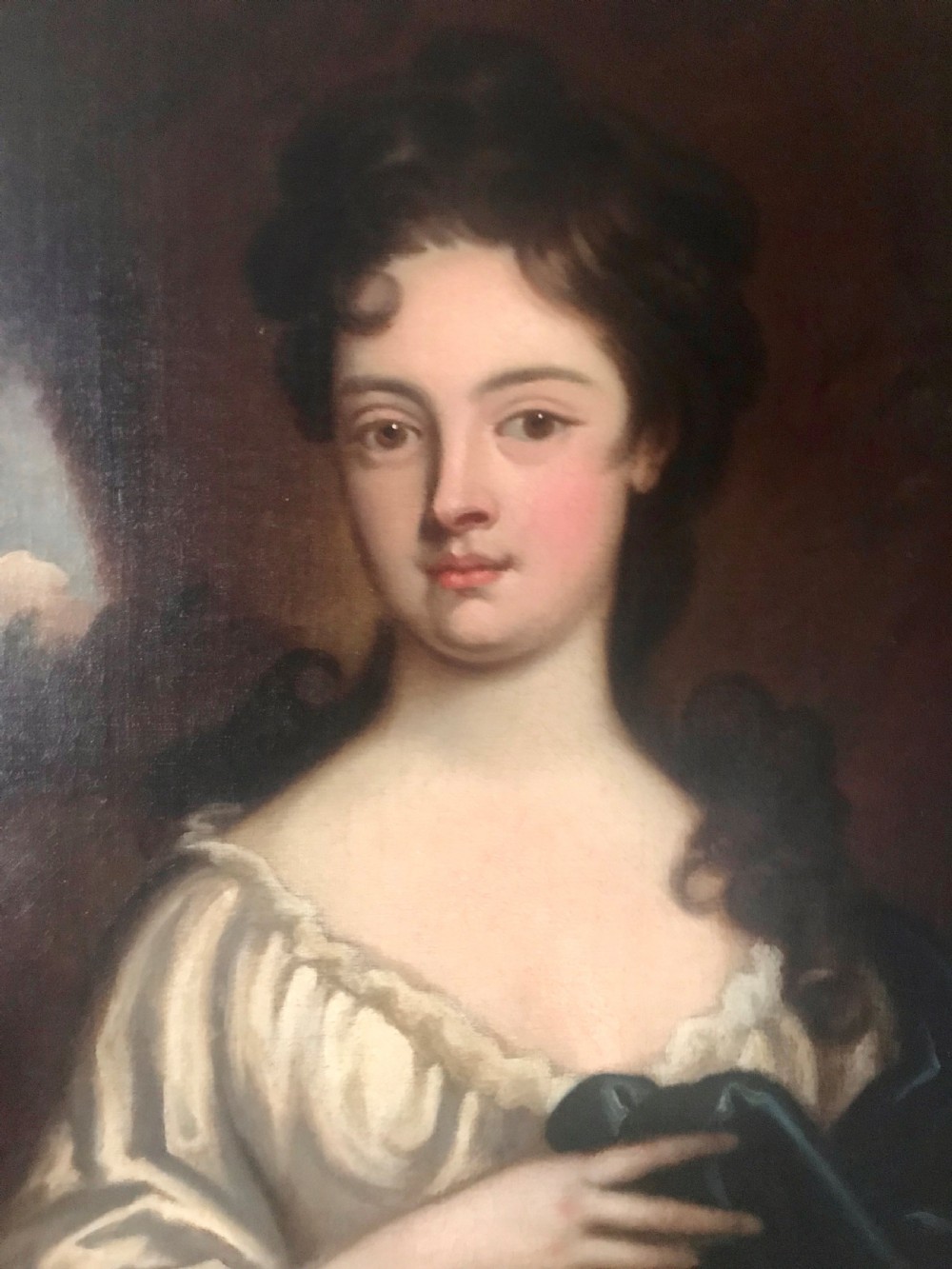An 18th-century oil portrait painting of a woman in a white gown with a blue drape, set within a carved gold gilt frame. View II