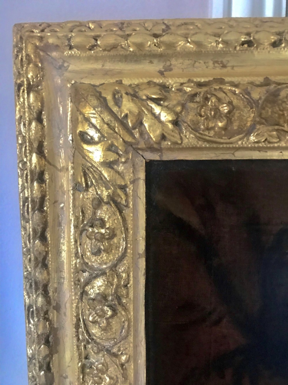 An 18th-century oil portrait painting of a woman in a white gown with a blue drape, set within a carved gold gilt frame. View V